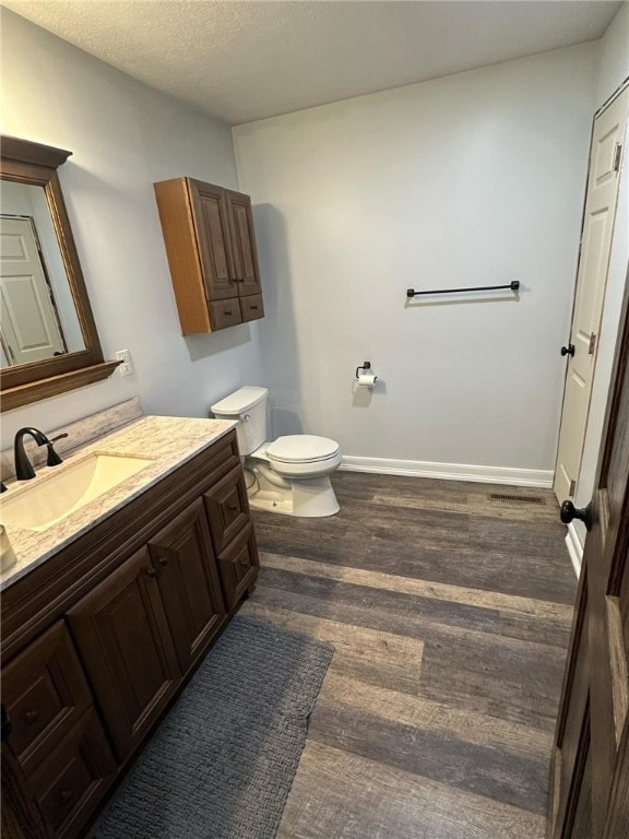 bathroom with baseboards, toilet, wood finished floors, and vanity