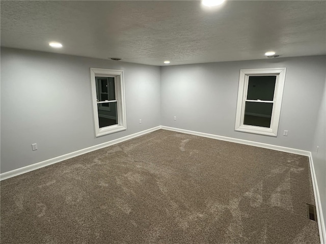 unfurnished room featuring recessed lighting, baseboards, dark carpet, and a textured ceiling