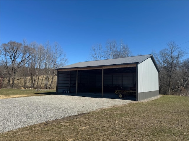 view of pole building featuring gravel driveway, a detached carport, and a lawn