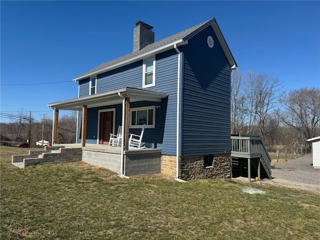 rear view of property featuring a yard, a porch, a chimney, and stairway