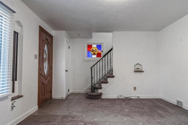 entrance foyer with stairway, carpet, visible vents, and baseboards