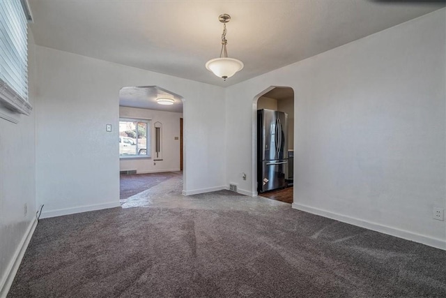 spare room with baseboards, arched walkways, and dark carpet