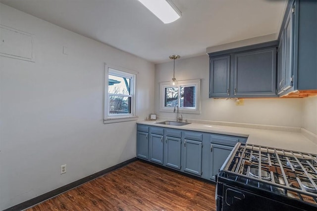 kitchen featuring blue cabinets, dark wood-type flooring, a sink, gas range oven, and baseboards