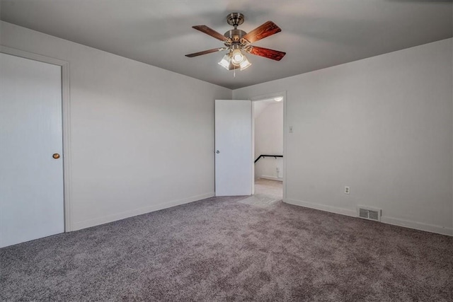 carpeted spare room with visible vents, baseboards, and a ceiling fan