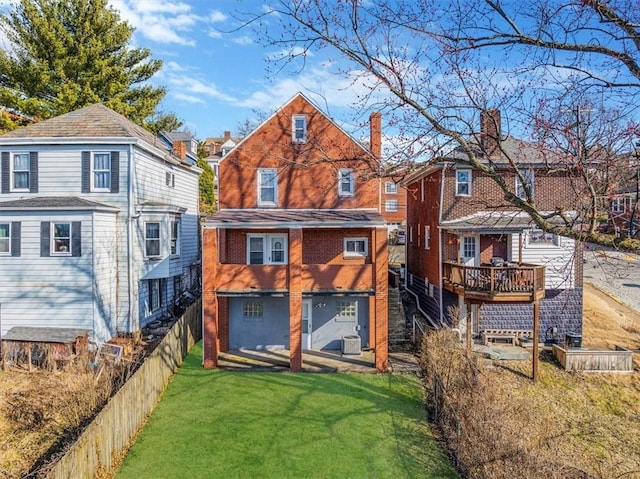 rear view of house with central air condition unit, fence, a yard, brick siding, and a chimney