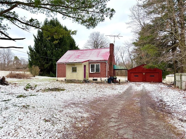 view of front facade with an outbuilding, driveway, entry steps, a detached garage, and a chimney