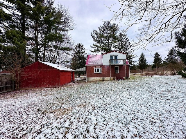 snow covered house featuring metal roof, an outbuilding, brick siding, and a gambrel roof