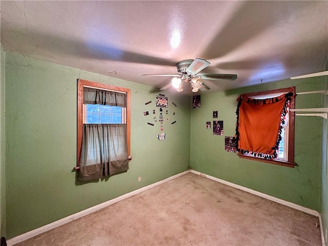 carpeted spare room featuring ceiling fan and baseboards