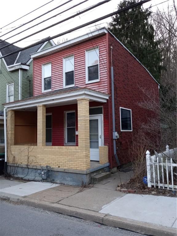 view of front facade with brick siding and fence