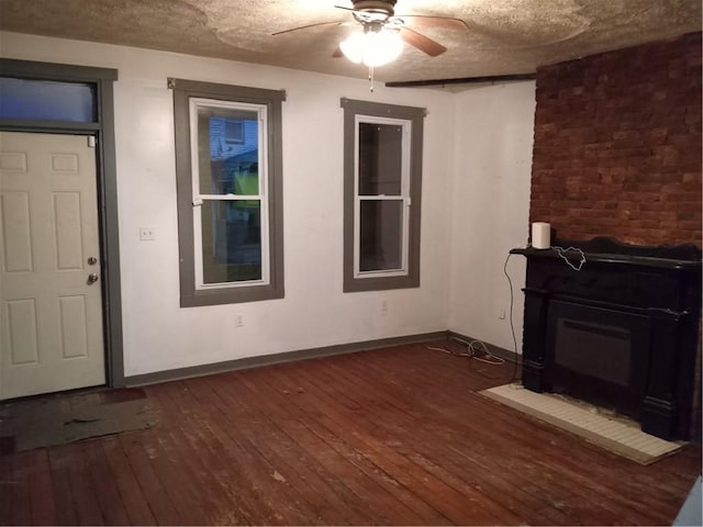 unfurnished living room featuring a ceiling fan, baseboards, a textured ceiling, and dark wood-style flooring