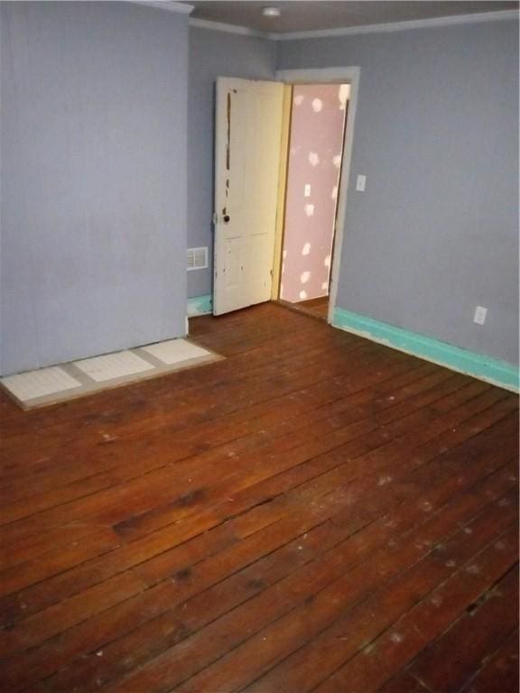 unfurnished room with visible vents, crown molding, baseboards, and hardwood / wood-style floors