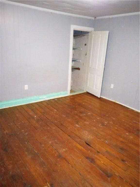 empty room featuring hardwood / wood-style floors, baseboards, and ornamental molding