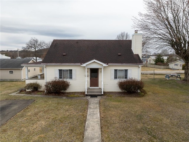 view of front of property with roof with shingles, a chimney, a front lawn, and entry steps