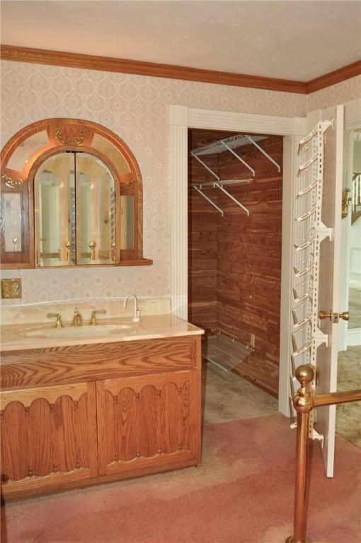 bathroom featuring crown molding, vanity, and wallpapered walls