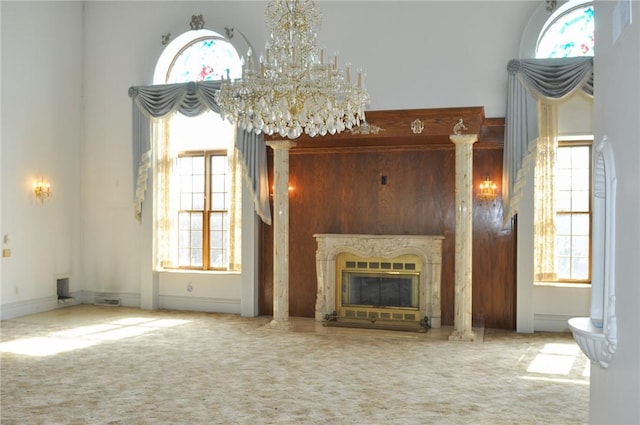 unfurnished living room featuring a high end fireplace, visible vents, baseboards, carpet, and a chandelier