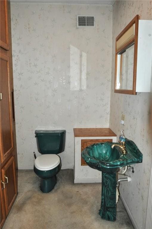 half bath featuring wallpapered walls, toilet, baseboards, and visible vents