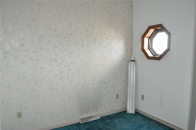 empty room with baseboards, visible vents, and dark carpet