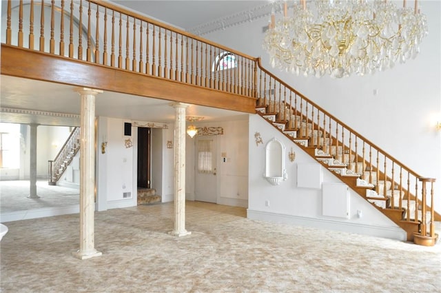 interior space featuring a high ceiling, stairs, ornate columns, and carpet floors