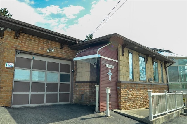 view of property exterior featuring brick siding, driveway, and a garage