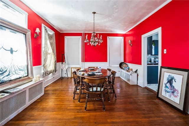 dining room with wainscoting, wood finished floors, a chandelier, and crown molding