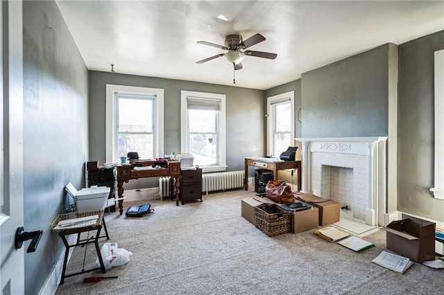 living area with a ceiling fan, radiator, a fireplace, and carpet flooring