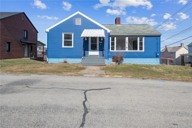 bungalow-style house with a chimney and a front yard