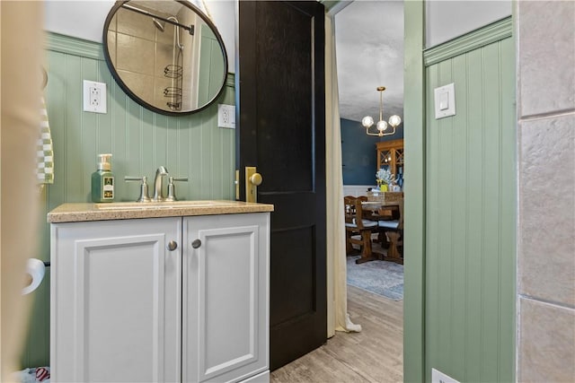 bathroom featuring a notable chandelier, wood finished floors, and vanity