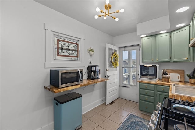 kitchen featuring light tile patterned floors, stainless steel microwave, fridge, and green cabinetry