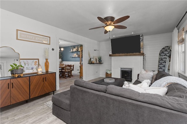 living room with a fireplace, light wood-style flooring, and a ceiling fan