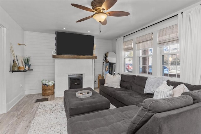 living area with a fireplace, wood finished floors, and ceiling fan