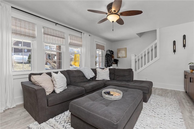 living room featuring stairway, plenty of natural light, baseboards, and light wood finished floors