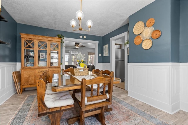 dining space featuring a chandelier, wainscoting, a textured ceiling, and wood finished floors