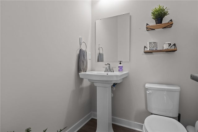 half bath featuring baseboards and toilet