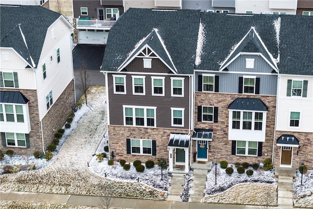 view of front of property with stone siding and roof with shingles