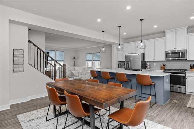 dining area with recessed lighting, stairway, baseboards, and wood finished floors