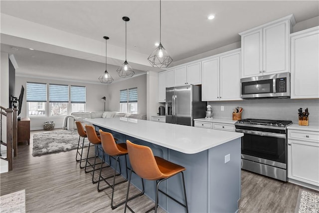 kitchen with a kitchen island, appliances with stainless steel finishes, white cabinetry, tasteful backsplash, and open floor plan