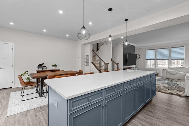 kitchen featuring a kitchen island, wood finished floors, open floor plan, recessed lighting, and light countertops