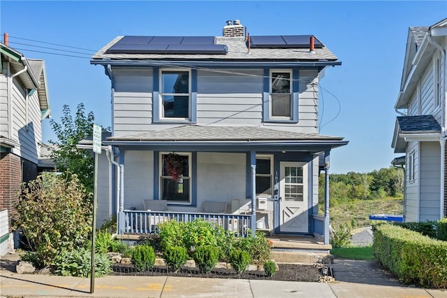 traditional style home featuring solar panels, a porch, a chimney, and a shingled roof