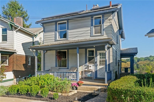 american foursquare style home featuring covered porch and solar panels