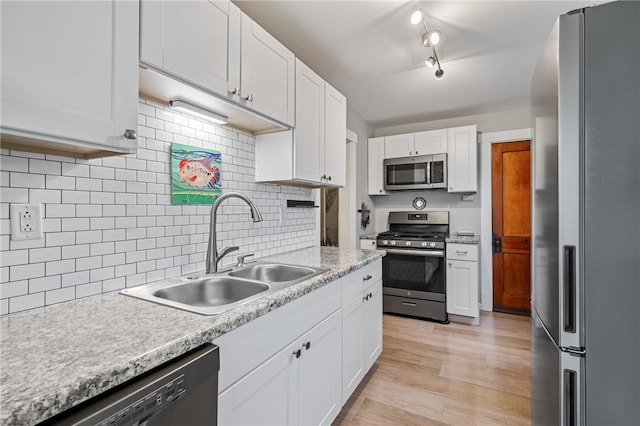 kitchen with light wood-style flooring, a sink, appliances with stainless steel finishes, white cabinets, and light countertops