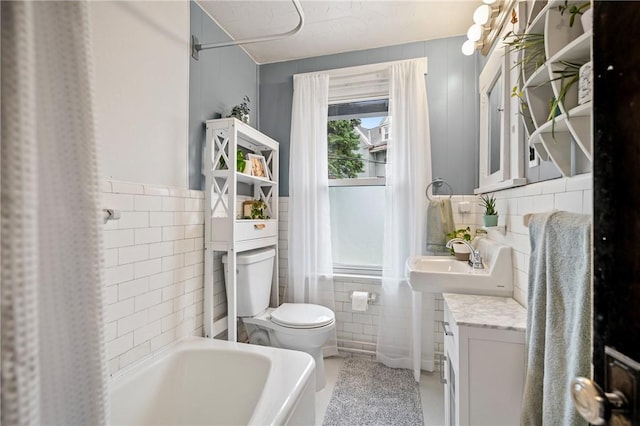 full bath featuring vanity, tile walls, and toilet