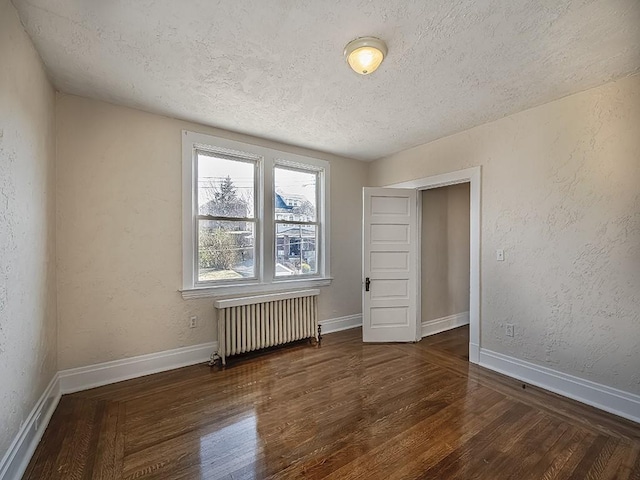 spare room with radiator, a textured ceiling, a textured wall, and wood finished floors