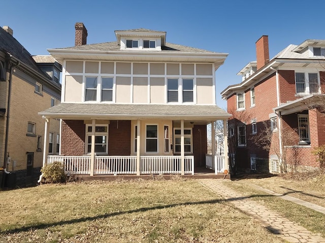 american foursquare style home with a porch, a front yard, and a shingled roof