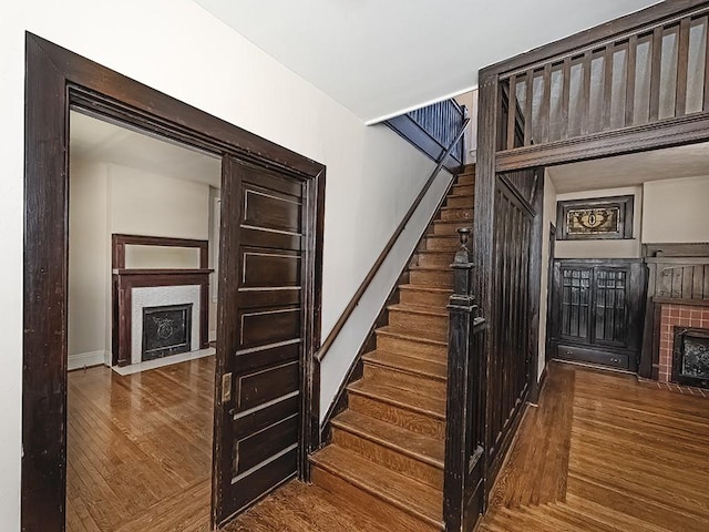 stairs with baseboards, a fireplace with flush hearth, and wood finished floors