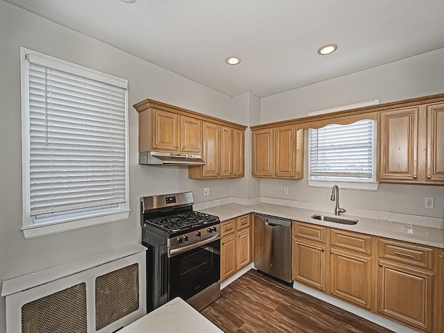 kitchen with a sink, under cabinet range hood, radiator heating unit, stainless steel appliances, and light countertops