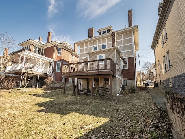 back of property featuring brick siding, a chimney, and a deck