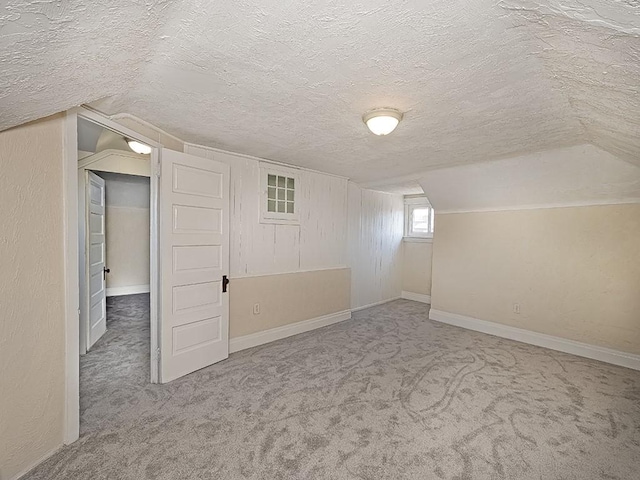 bonus room with a textured wall, baseboards, carpet, and a textured ceiling