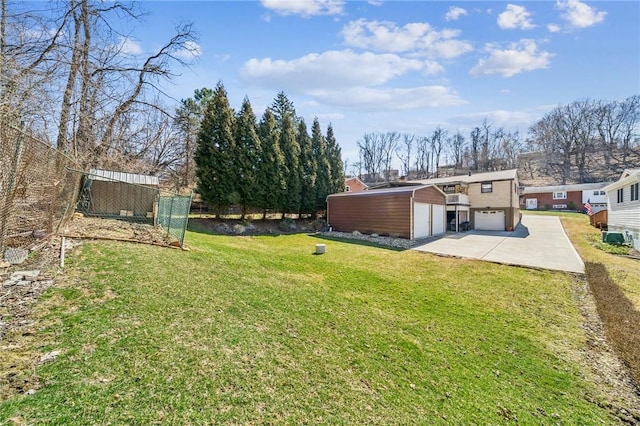 view of yard featuring a garage, an outbuilding, and fence