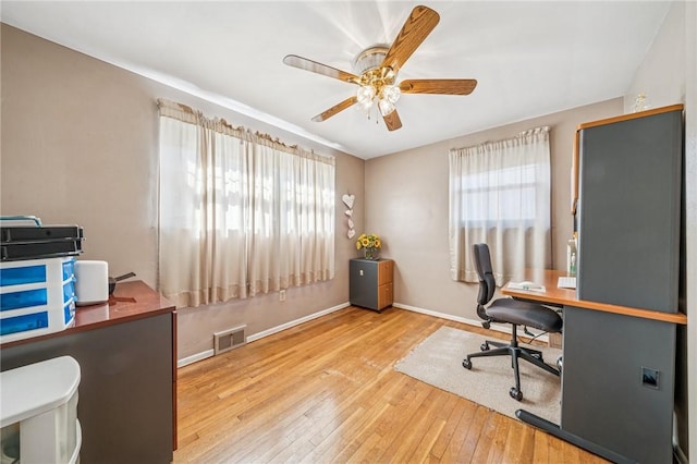 office space with ceiling fan, visible vents, a healthy amount of sunlight, and hardwood / wood-style floors