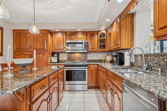 kitchen featuring a sink, dark stone countertops, brown cabinetry, and stainless steel appliances